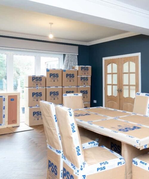 A packed up dining room with PSS International Removals logos on it, before an international removals
